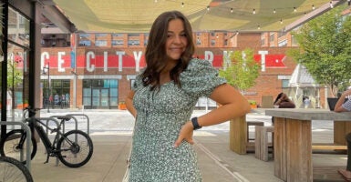 Laken Riley, a college coed, poses in front of a city market in a flower blouse.