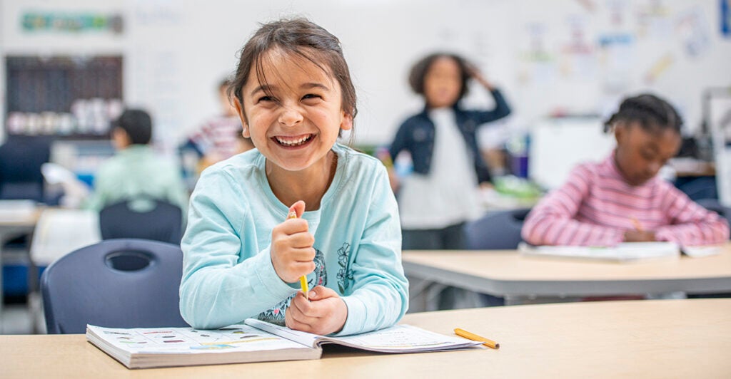 Young Girl in Class at Her Desk Laughing