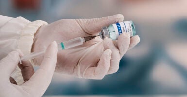 A doctor uses a syringe to prepare a COVID-19 vaccine.