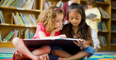 Two girls read book in children's library