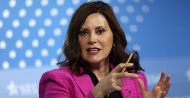 Gretchen Whitmer in a pink blazer gestures with a pencil in her right hand