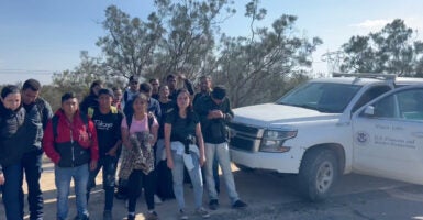 A group of illegal immigrants stand on the side of the road next to a Border Patrol truck.