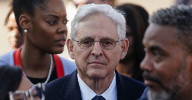 Merrick Garland looks ahead in a pin-stripe suit with a tie.