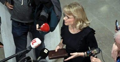 Paivi Rasanen in black holds a Bible accosted by press