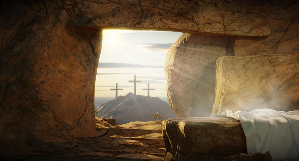 Three crosses on Golgatha and an empty tomb with a shroud and a rock pulled across the tomb entrance