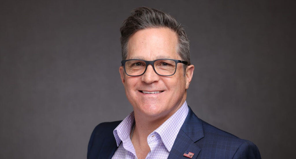 Russ Salerno in a blue suit and glasses wearing an American flag pin