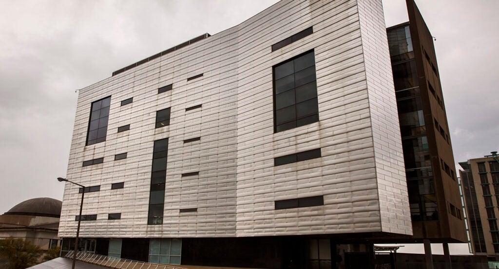 A large grey building with a cloudy rainy sky