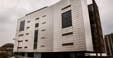 A large grey building with a cloudy rainy sky