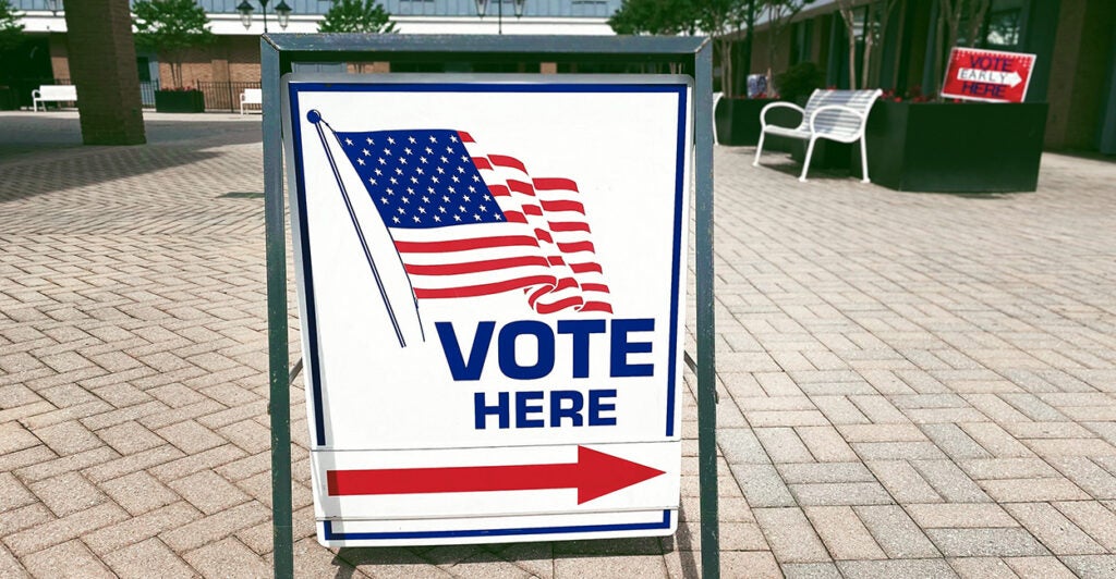 A sign reads "vote here" with a red arrow pointing to the right.