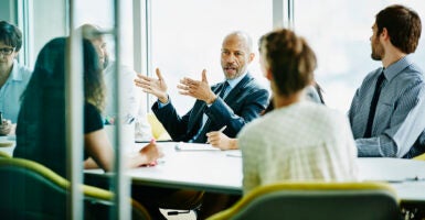 Corporate executive speaks in a suit to employees in dress clothes in a boardroom