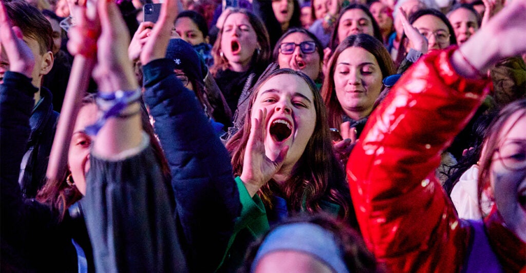 Young female rallygoers in France smile and shout to celebrate abortion enshrined in the constitution