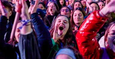 Young female rallygoers in France smile and shout to celebrate abortion enshrined in the constitution