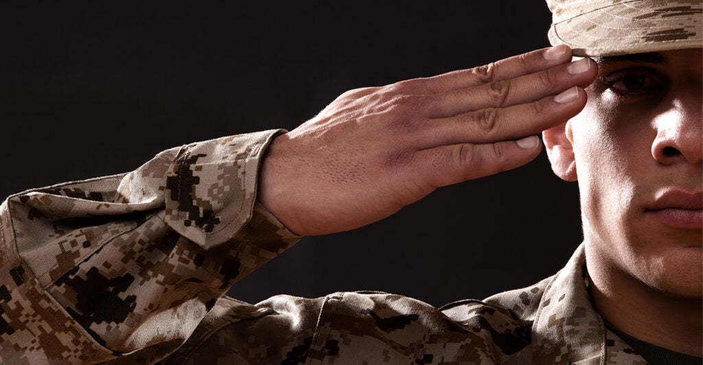 Half the face of a soldier is seen saluting.