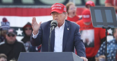 Former President Trump at A Campaign Rally outdoors with a crowd behind him