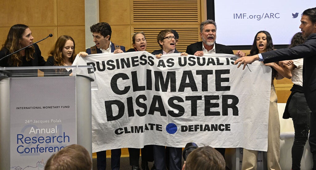 Activists hold a sign reading "Business as usual is climate disaster" at IMF summit.