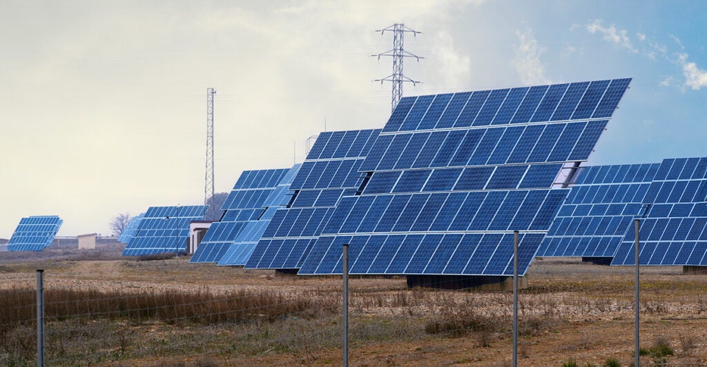 Solar panels are seen stretched over a large area of sandy dirt.