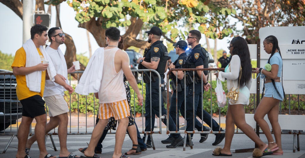 Police and college age men and women are seen walking outside in Miami Beach.