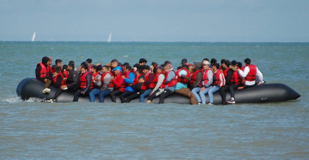 Dozens of migrants with lifejackets overflow an inflatable raft in the English Channel