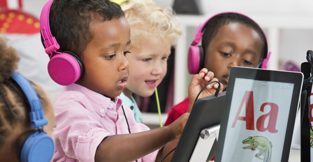 Toddlers using ipads and headphones.