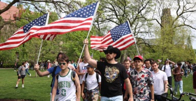 University of Chicago counter-protesters raise American flags into the air, wearing t-shirts.