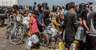 A group of men and boys stand in line with water jugs in Gaza.