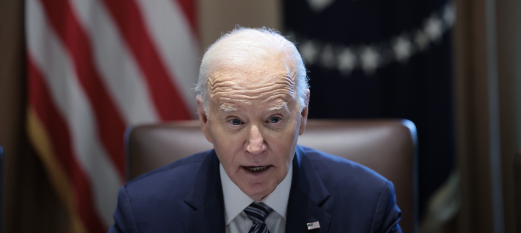 President Joe Biden sitting at a desk with a U.S. flag behind him