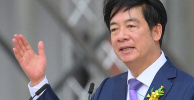 Taiwan's President Lai Ching-te In a suit and purple tie with his hand raised halfway in the air