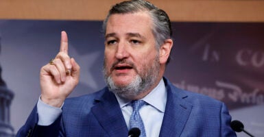 Ted Cruz raises his finger in a blue suit