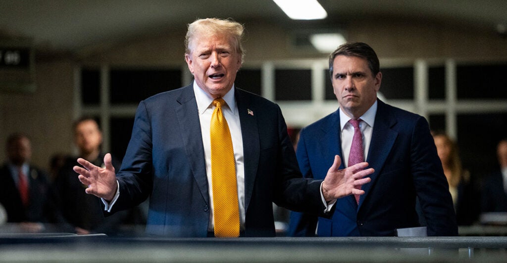 Former President Donald Trump speaks outside the courtroom in a yellow tie and dark blue suit.