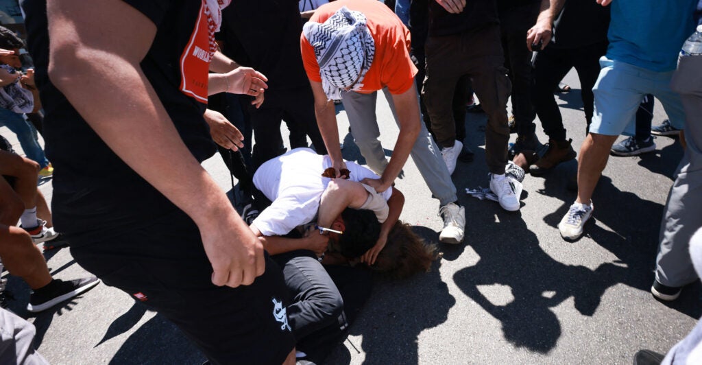 two people fighting on the ground in the middle of a crowd of protesters