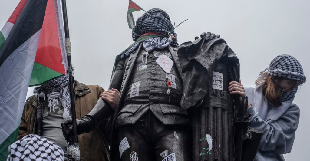 pro-Hamas protesters wrap Palestinian flag and Keffiye around the statue