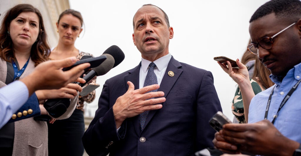 Rep. Bob Good In a suit standing in a group of reporters with microphones