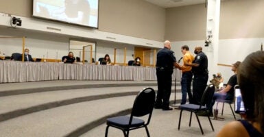 Police escort Jeremy Story out of a school board meeting