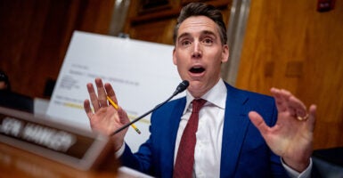 Sen. Josh Hawley holds up his hands and speaks into a microphone at a Senate hearing.