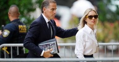 Hunter Biden in a suit stands behind his wife, Melissa Cohen, in a white dress shirt