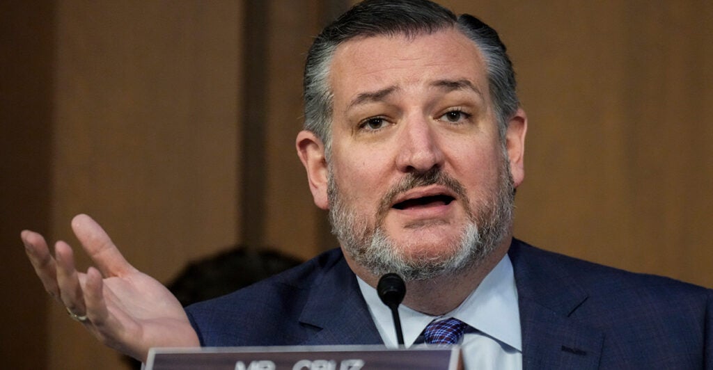 Ted Cruz in a suit gestures with his left hand