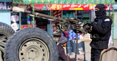 A Taliban soldier stands guard on a vehicle outside a mosque.