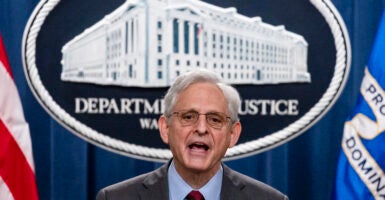 Merrick Garland speaks at a podium in front of the Department of Justice emblem.