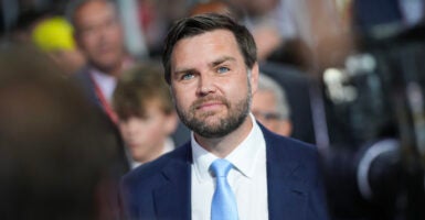 J.D. Vance looks upward, wearing a light blue tie and navy blue suit.