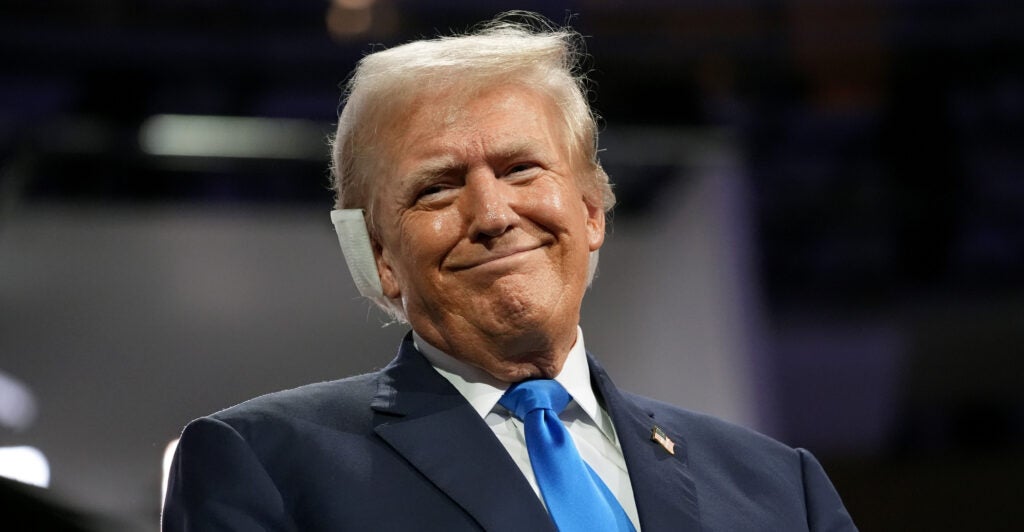 Donald Trump smiles at the camera with a bandaged right ear.