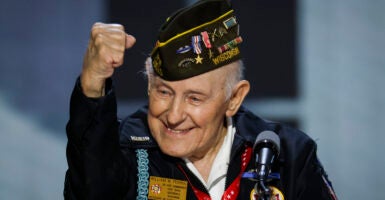 WWII Veteran Sergeant William Pekrul pumps his fist and smiles while standing at the podium on stage.