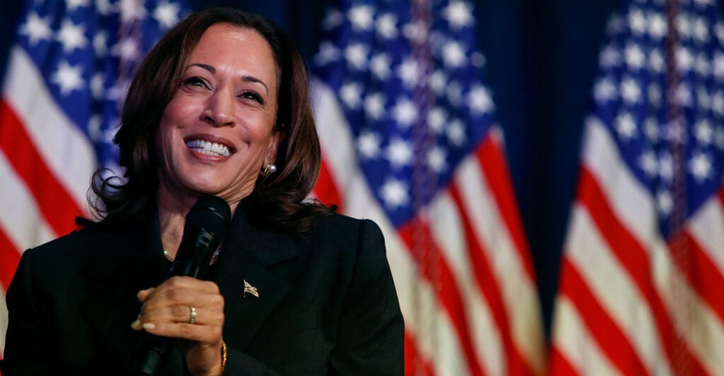 Kamala Harris smiling and holding a microphone.