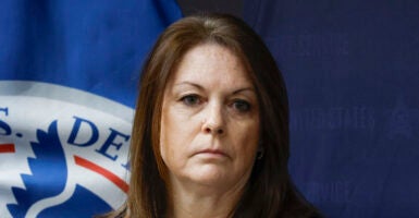 Secret Service Director Kimberly Cheatle stares into the camera in front of a seal for the Department of Homeland Security.