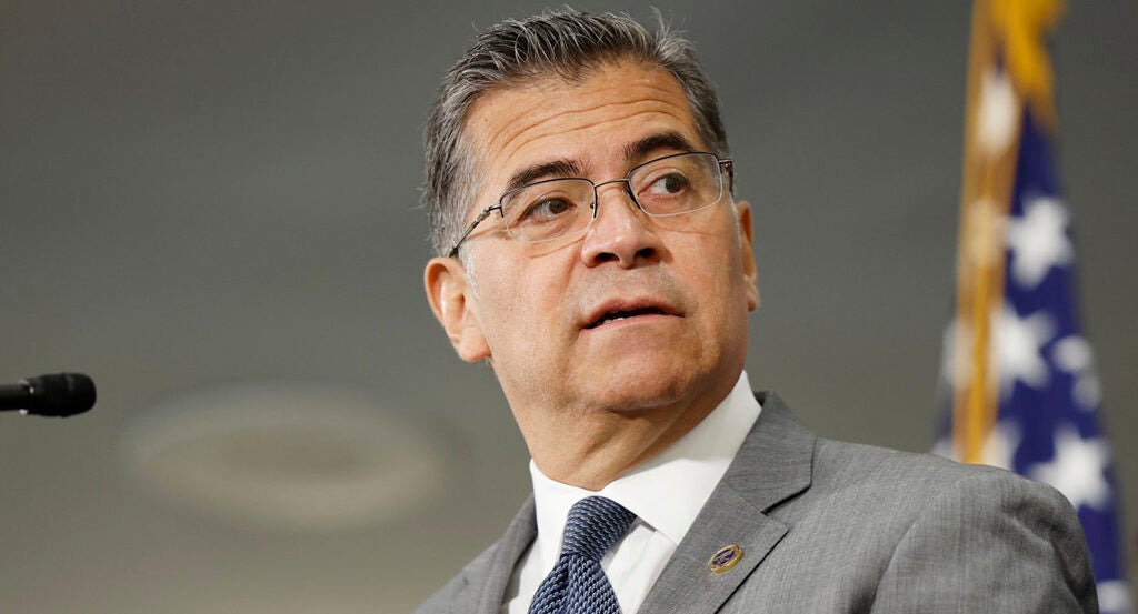 Xavier Becerra in a grey suit looks to the right