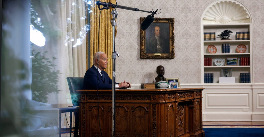 Biden sits at his desk in the Oval Office.