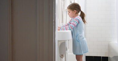 A little girl washes her hands.