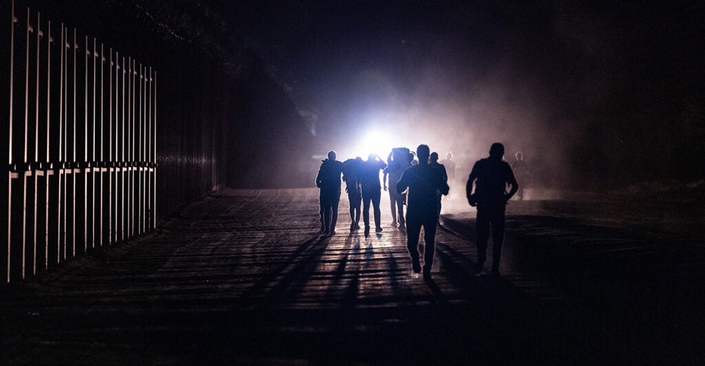 Immigrants cross the border on a railroad.