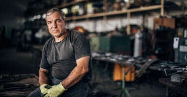 Mature man sits in factory workshop alone.