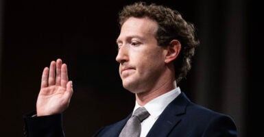 Mark Zuckerberg raises right hand for oath in black suit.