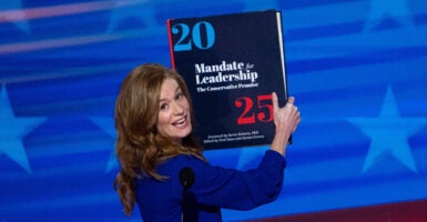 Michigan State Senator Mallory McMorrow holds up a "Project 2025" book as she speaks.